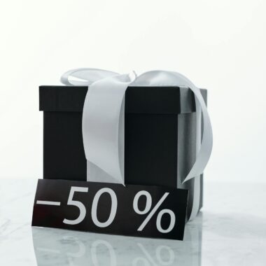 Elegant black gift box tied with a white ribbon, featuring a 50% discount tag.