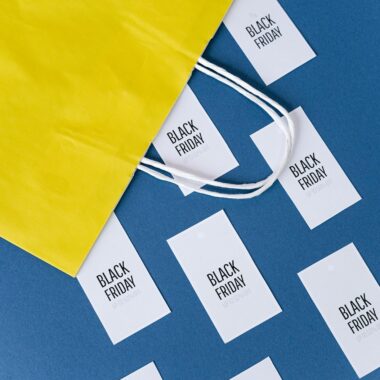 Flat lay of a yellow shopping bag with Black Friday cards on a blue background.