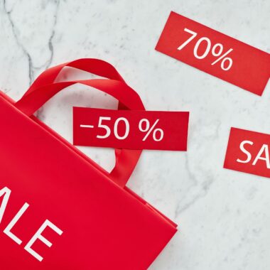 Red shopping bag and discount cards with percentages for promotional sale.