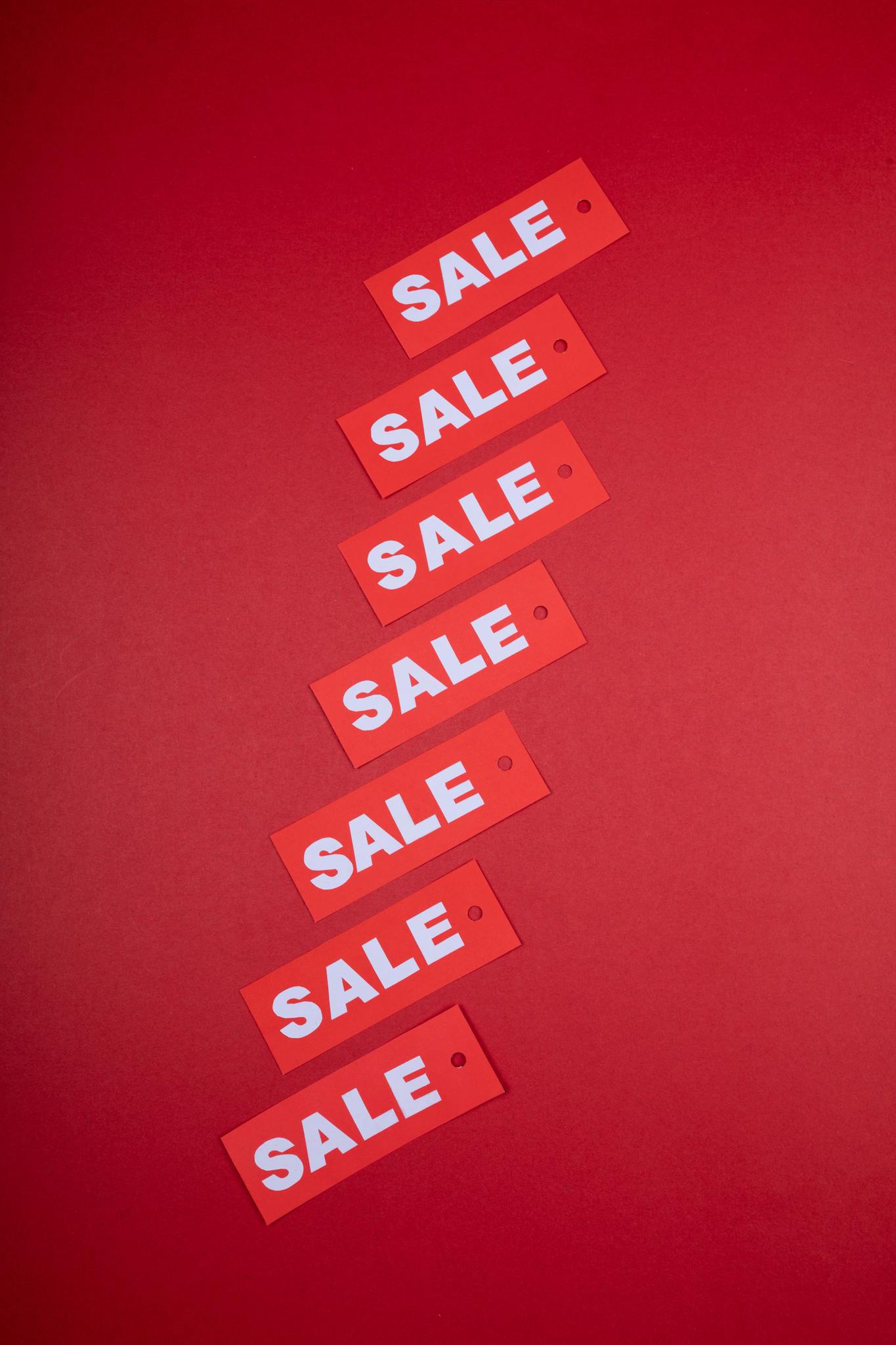 Vertical arrangement of red sale tags on a vivid red background, ideal for retail promotions.